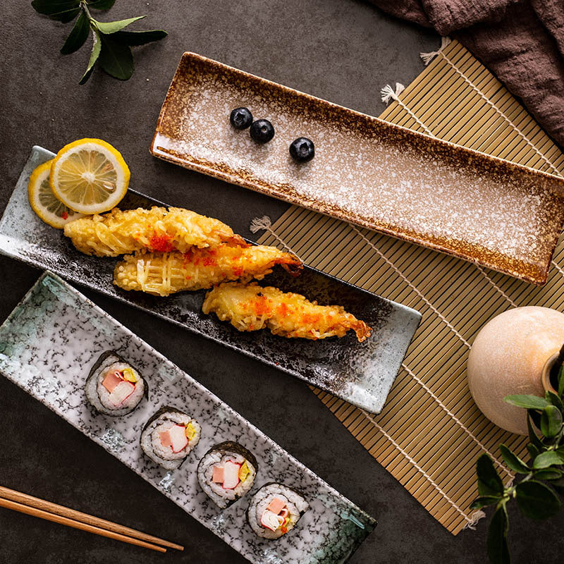 Boat-shaped ceramic sushi plate with lifted ends and a dark reactive glaze finish