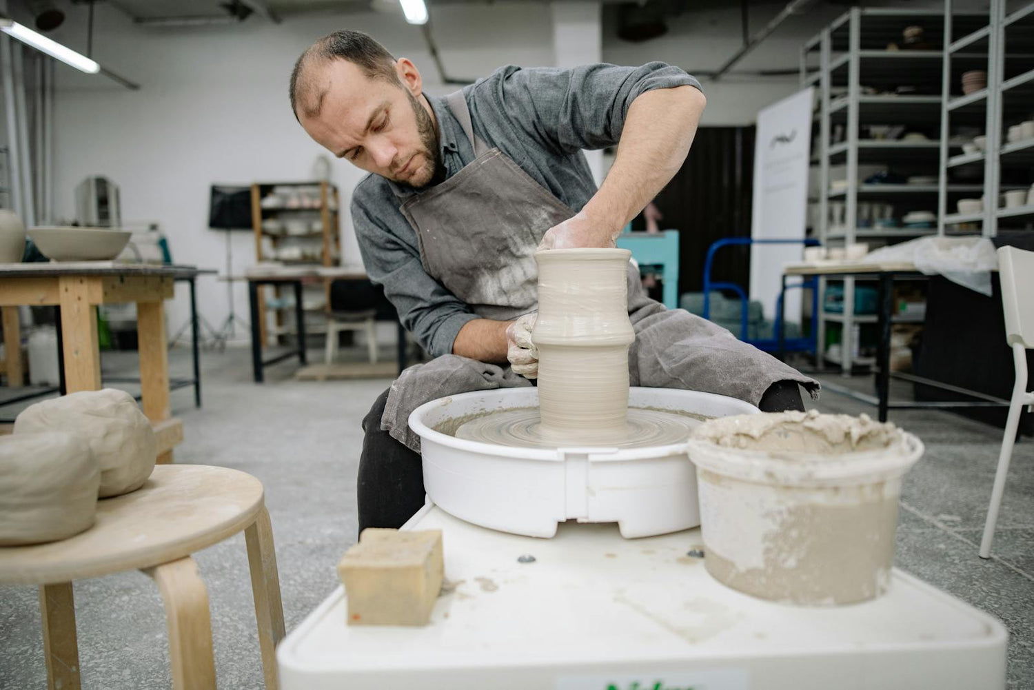 A potter's hands shaping a vessel on the wheel